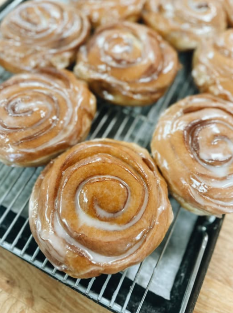 Glazed cinnamon rolls cooling on a rack
