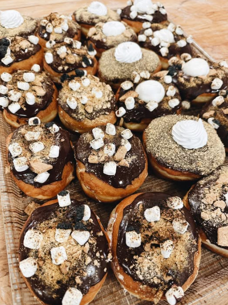 Tray of s'mores doughnuts topped with marshmallow and graham crumble